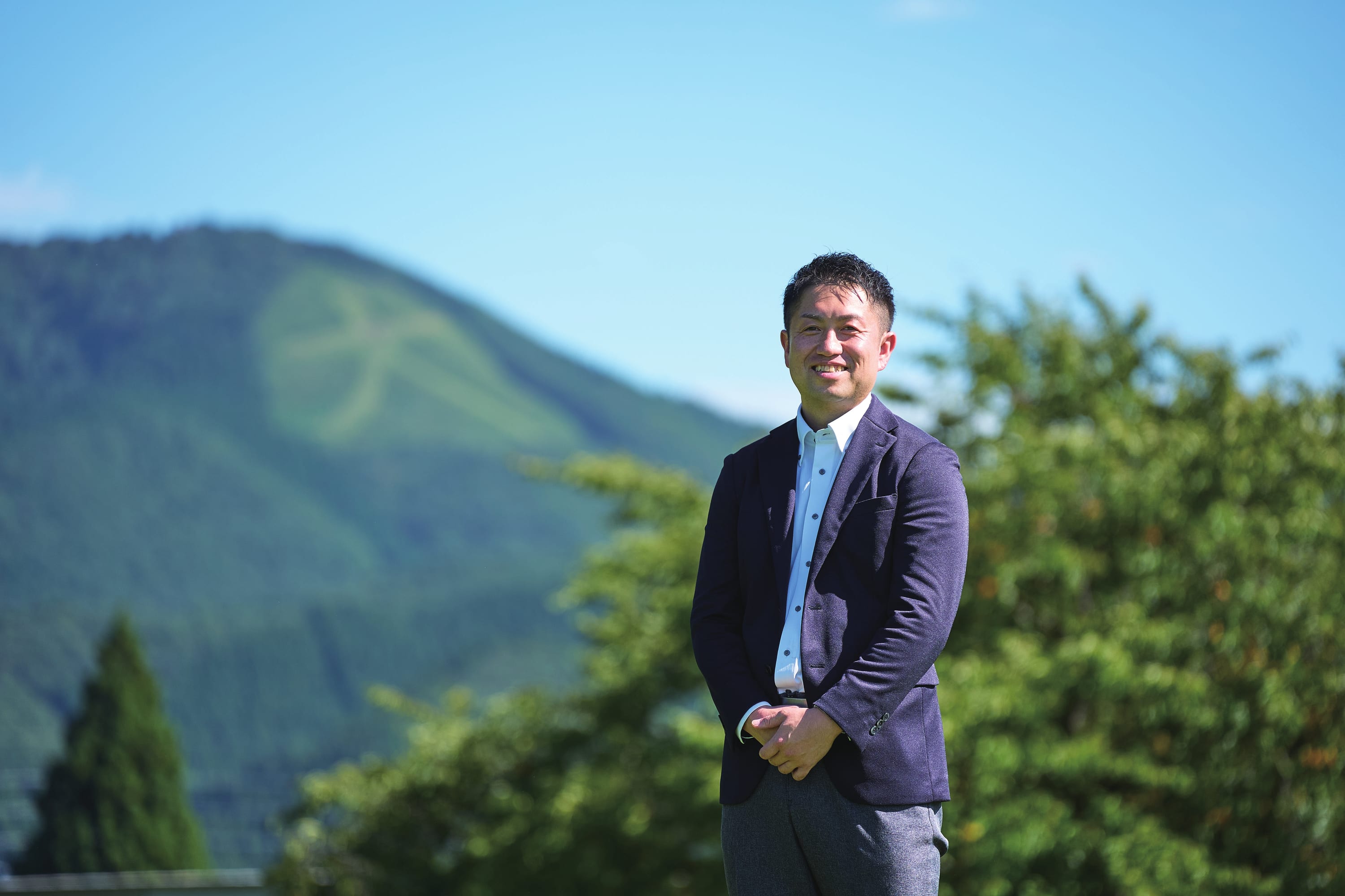 大館の山並みを背に立つ佐藤和幸